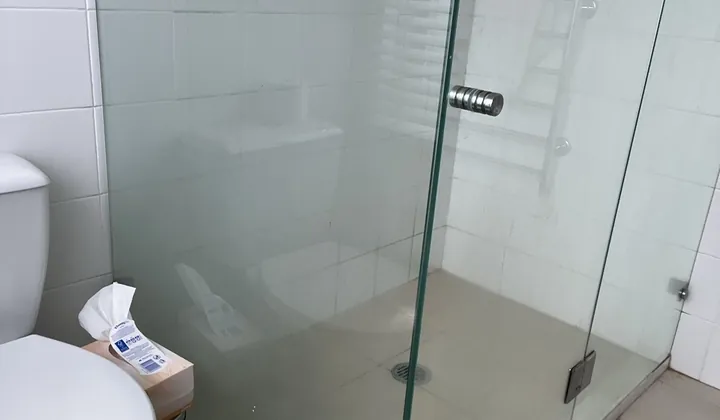 Compact ensuite with a frameless glass shower beside a toilet