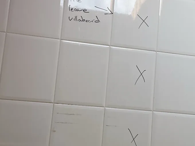Old bathroom wall tiles marked up in pen for removal before a renovation