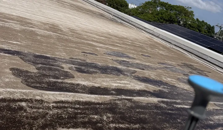 Pump sprayer on the edge of a flat roof with wet patches during a leak check in Northmead