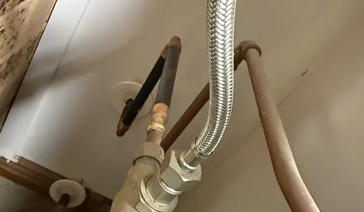 Braided hose and isolation valve connected under a hot water tank