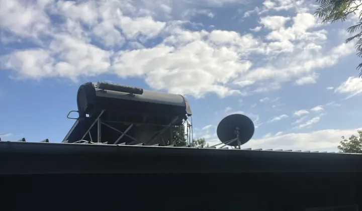 Solar hot water tank and frame on a roof beside a satellite dish in South Turramurra
