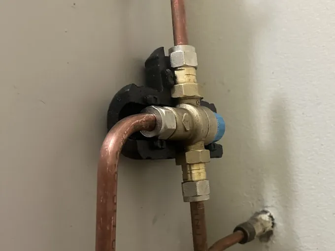 Tempering valve with copper pipework fixed to the side of a hot water tank in Bankstown