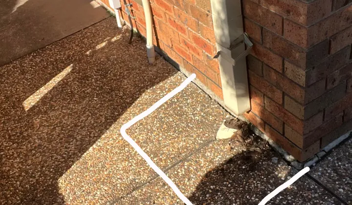 Downpipe on a brick corner with the concrete marked out around its base in Ingleburn