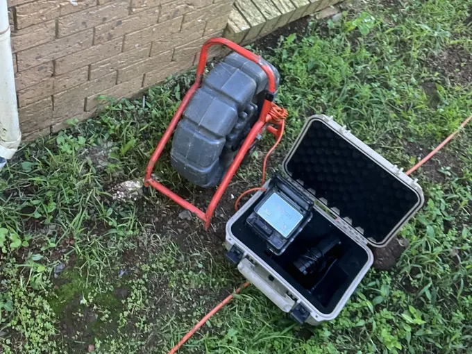 Drain camera reel and its monitor set up on the grass beside the house in Rosemeadow