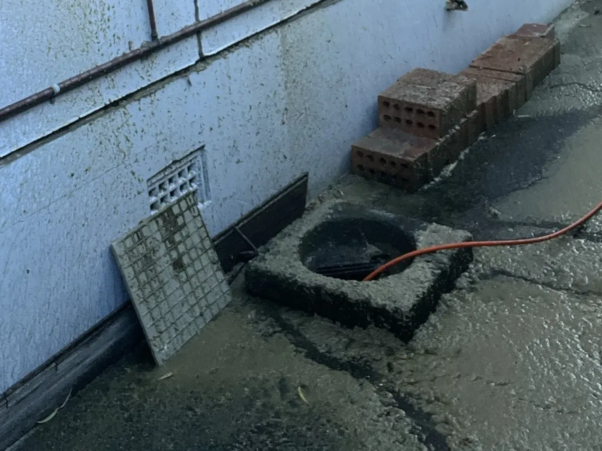 Surface drain opened up with its grate lifted out on a wet side path in Belmore