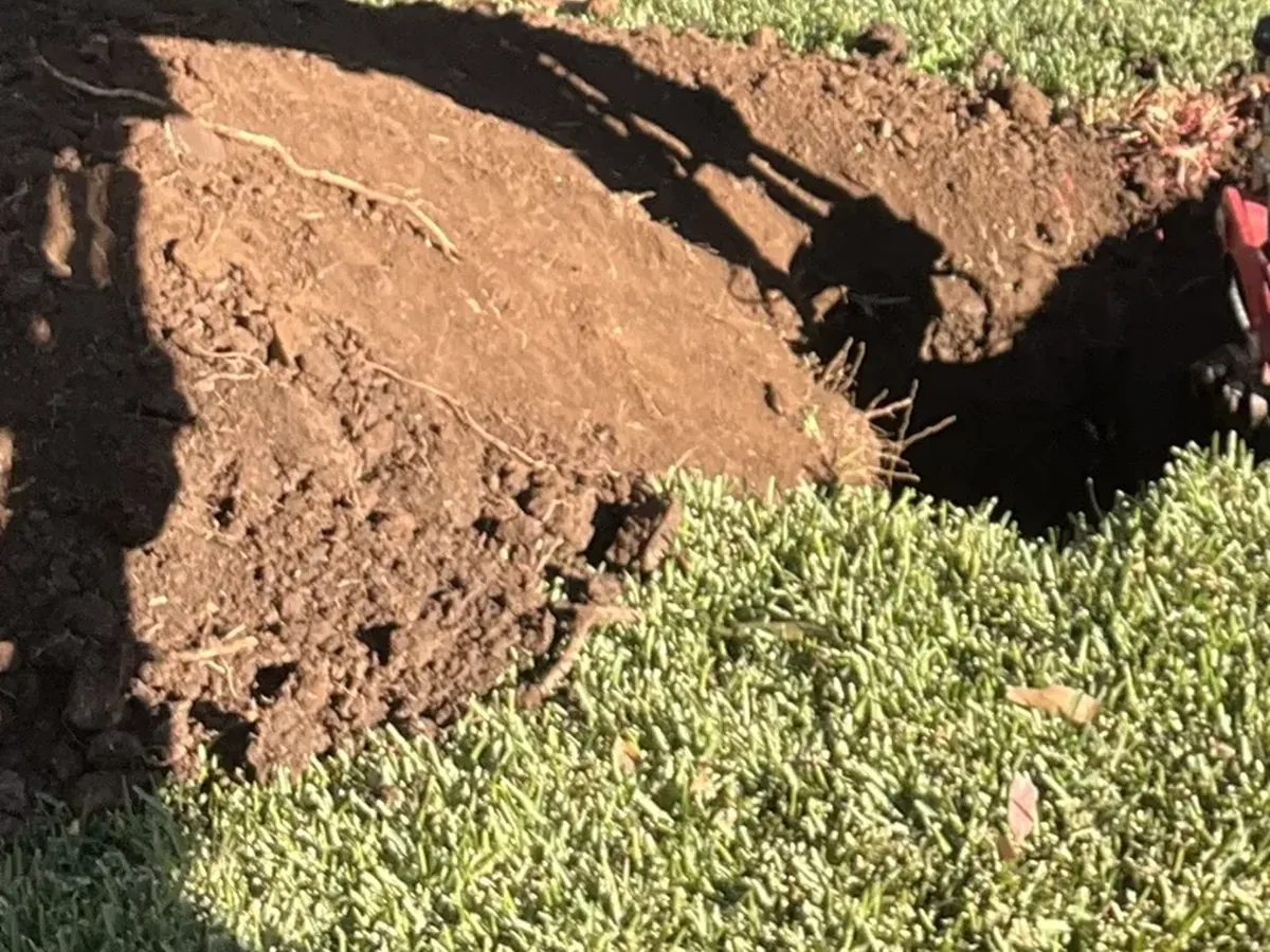 Hole opened up in a front lawn with the soil piled beside it in Bradbury