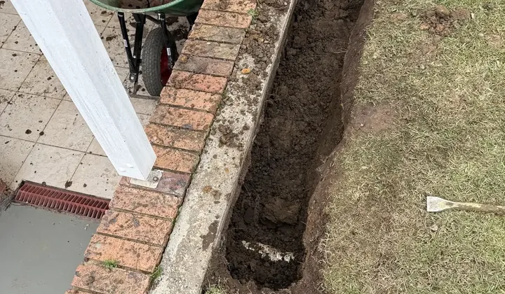 Trench dug beside brick garden edging for a new storm water pipe in Cromer