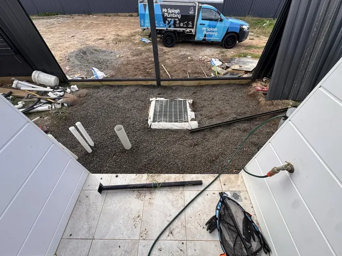 Finished stormwater pit grate set in blue metal gravel with the Mr Splash ute behind in Wilton