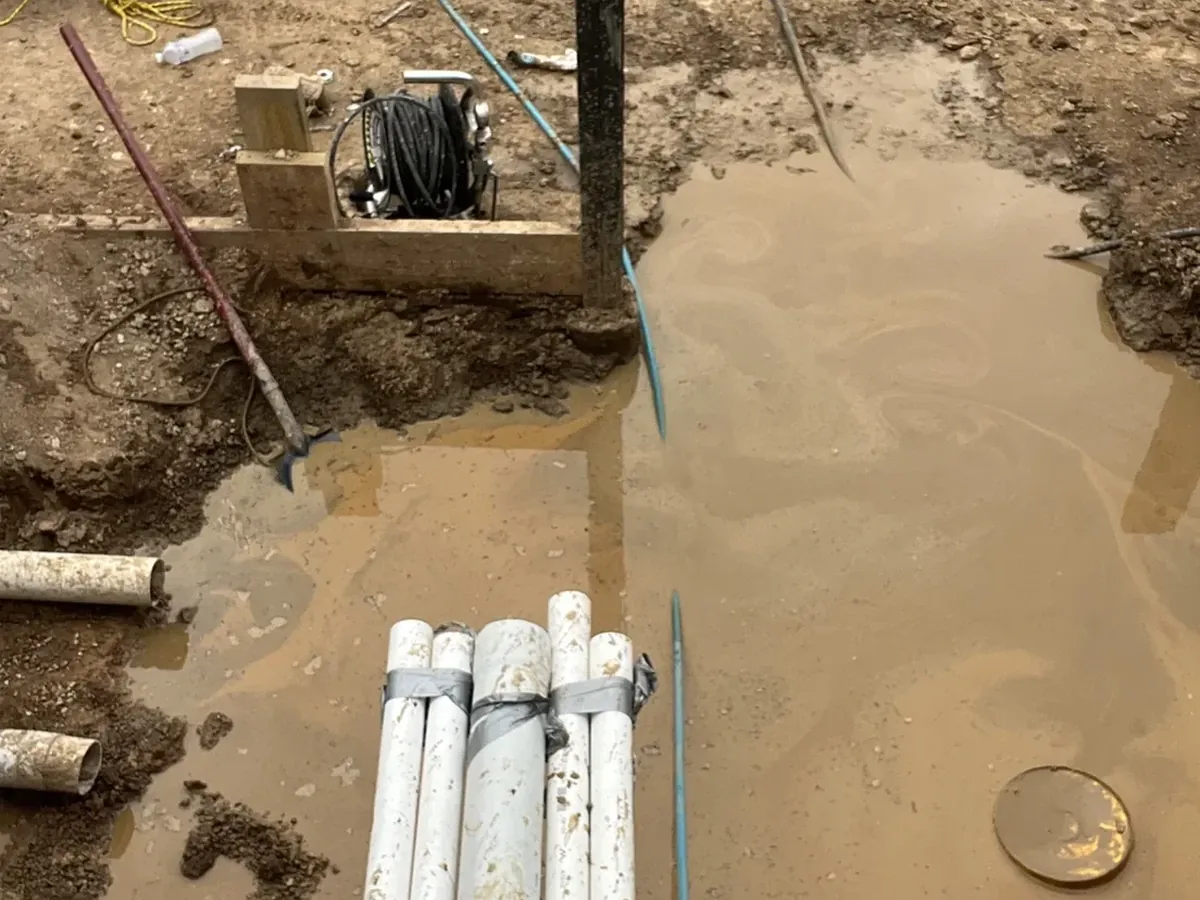Rain water pooled in an open excavation with new storm water pipes stacked ready in Wilton