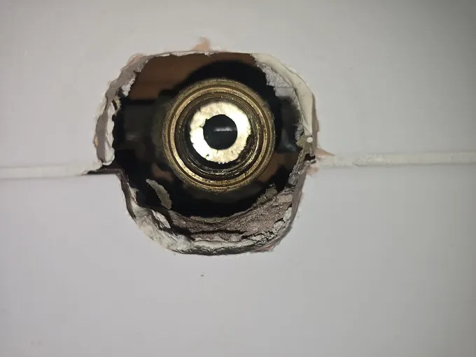 Brass tap body showing through a hole opened in the wall tiles in Stanhope Gardens