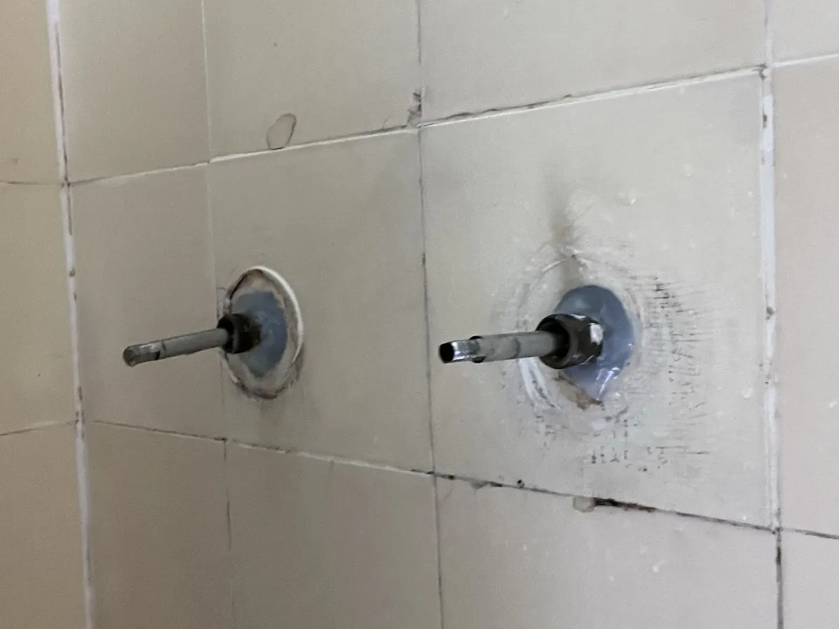 Shower tap spindles with their handles taken off, on a tiled wall in North Parramatta