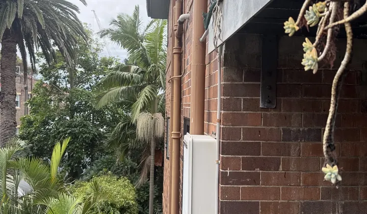 Continuous flow hot water unit and its pipes on the brick wall of an apartment block in Bondi Beach