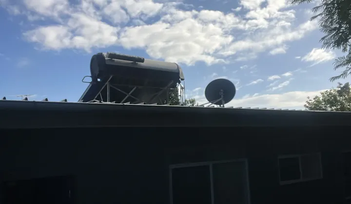 Solar hot water tank and frame on a roof beside a satellite dish in South Turramurra
