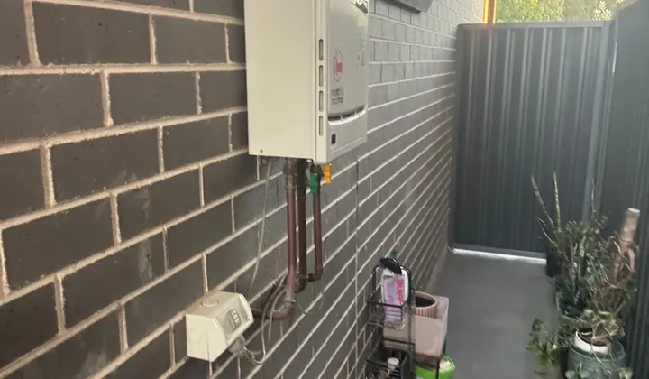 Existing continuous flow gas hot water unit and its copper pipes in a side passage in Oran Park