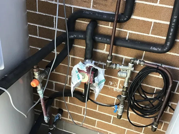 Brass valves and pipework on the water supply beside a hot water system in Enfield