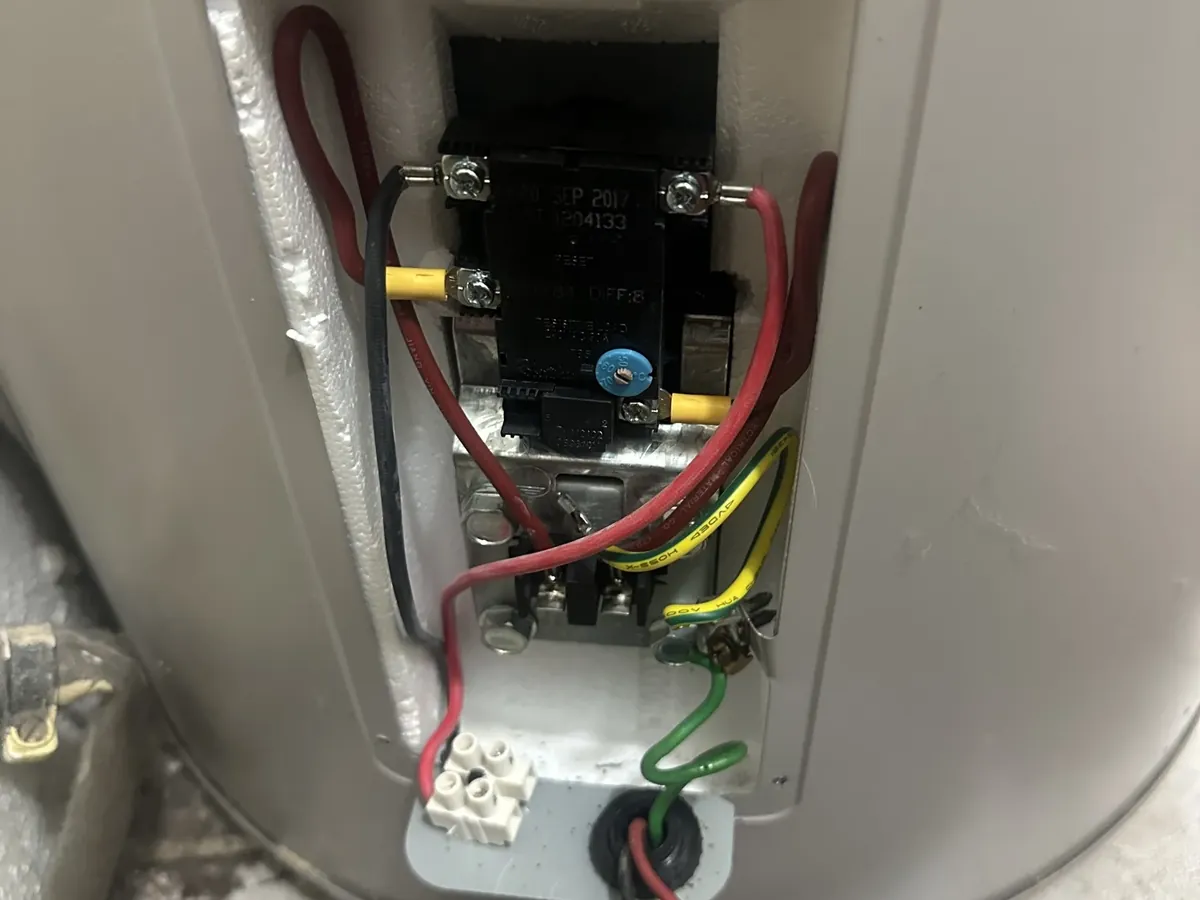 Thermostat and wiring exposed behind the element cover of an electric tank in Bankstown