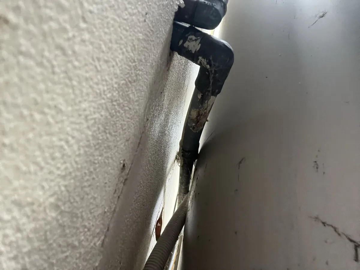 Old black lagged pipe running down the side of a hot water storage tank in Macquarie Fields
