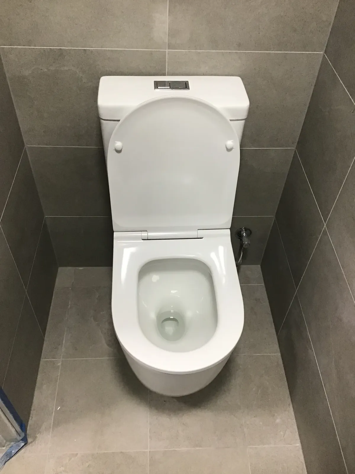 Back-to-wall toilet suite with a dual flush cistern in a grey tiled bathroom in Northmead