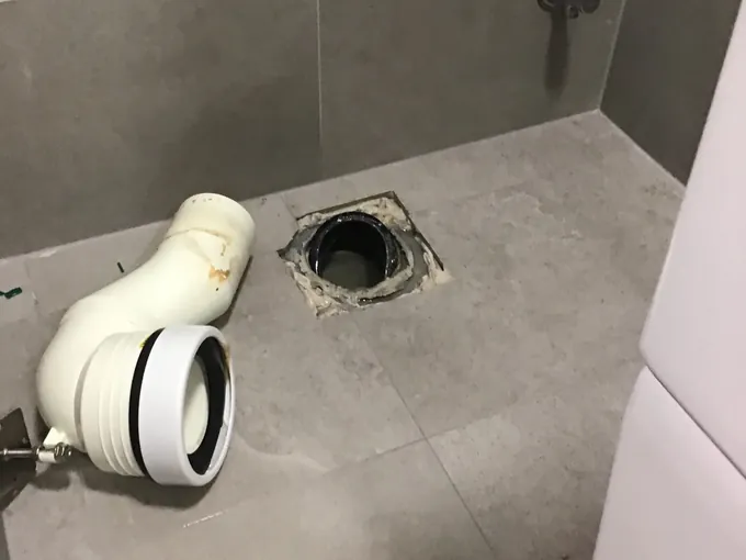 Toilet pan removed, with the pan connector lying beside the floor waste in Northmead