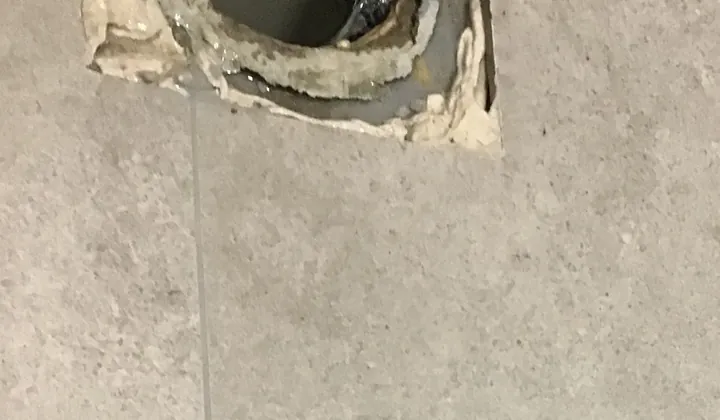 Drain opening in the tiled floor where a leaking toilet pan was lifted off in Northmead