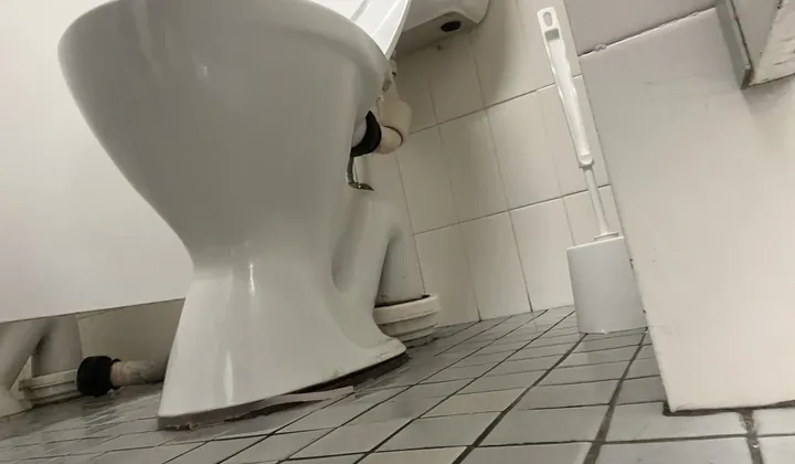 Low view of a toilet pan base and its drain connector in a Liverpool washroom
