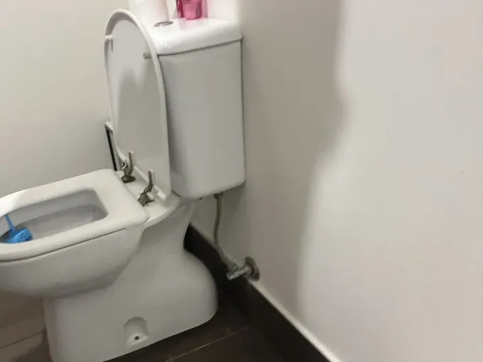 Toilet with its seat up and the stop tap on the wall beside it in Beverly Hills