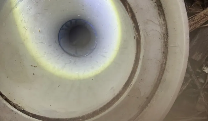 Torch light shining down the opened drain pipe during the clear in Yagoona