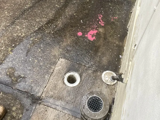 Sewer inspection openings and the overflow gully opened on the wet concrete path in Roselands