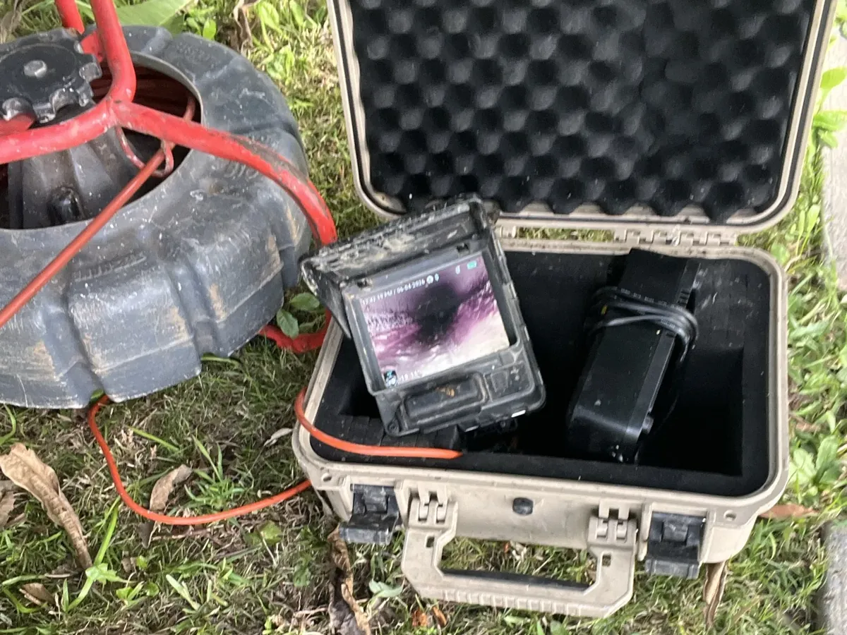 Drain camera reel and monitor case set up on the lawn beside the sewer opening in Padstow