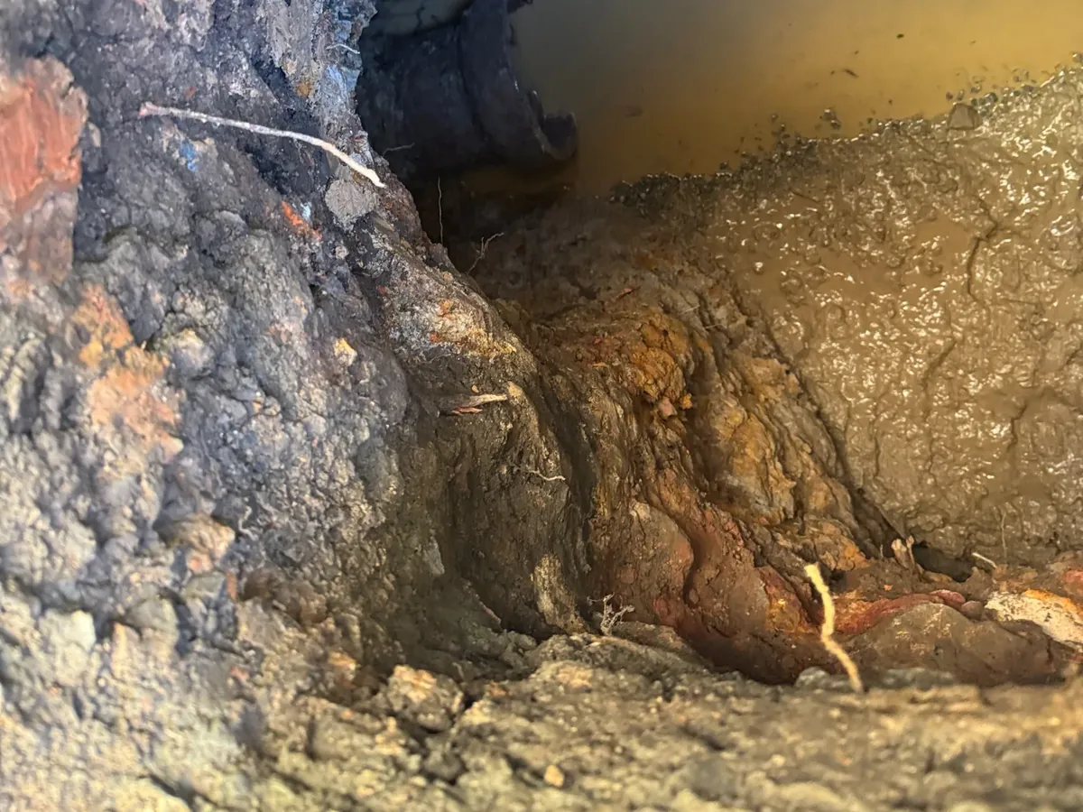 Old terracotta sewer pipe exposed at the bottom of a muddy excavation in Newtown