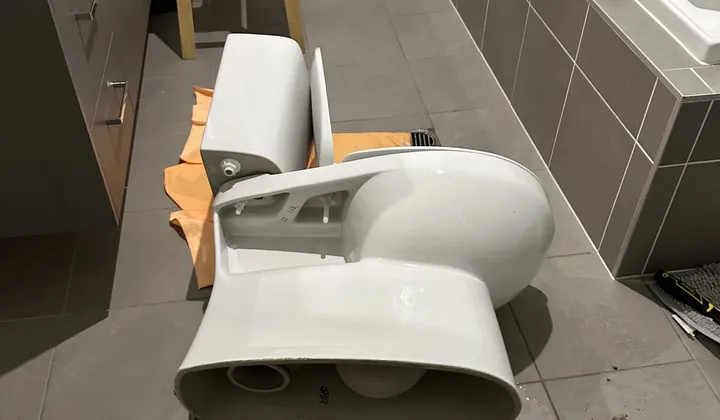 Toilet pan and cistern lifted off onto a drop sheet on a bathroom floor in Riverstone