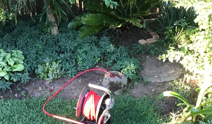 Hose reel from the jet blaster run into a garden drain riser in Casula