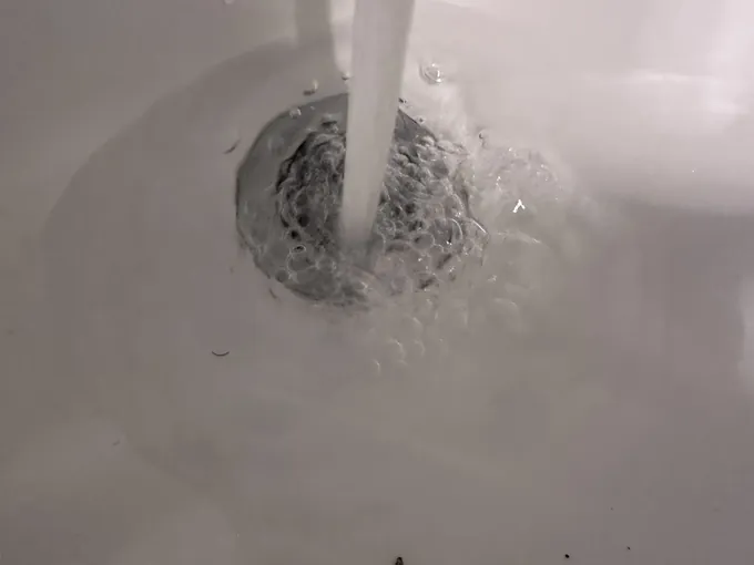Tap water draining freely down a white tub waste in Blacktown