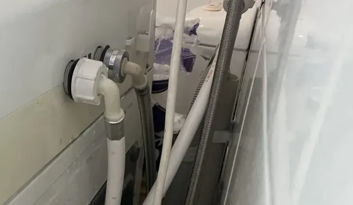 Water hoses connected at the back of a top loader washing machine in Newtown