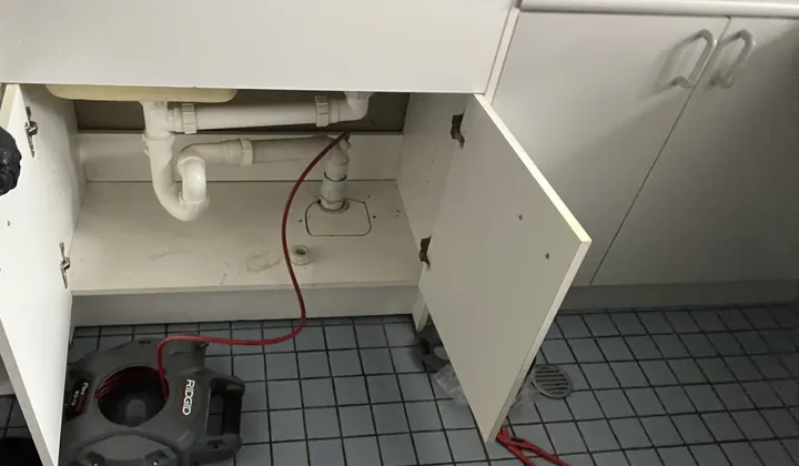 Drain machine cable run into the waste pipe under a laundry tub in Glebe