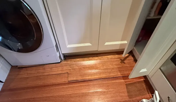Floorboards lifting from a leak beside a front loader washing machine in Double Bay