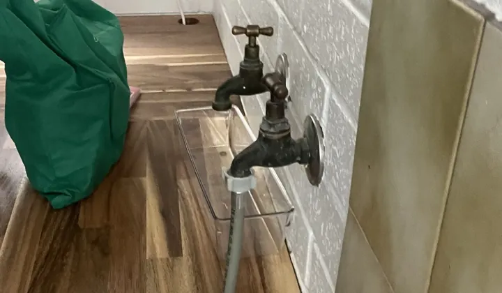 Brass laundry tap with a grey hose connected above a stainless tub in Stanmore