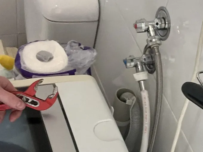 Plumber's wrench over a top loader beside its wall taps and hoses in a Newtown bathroom laundry