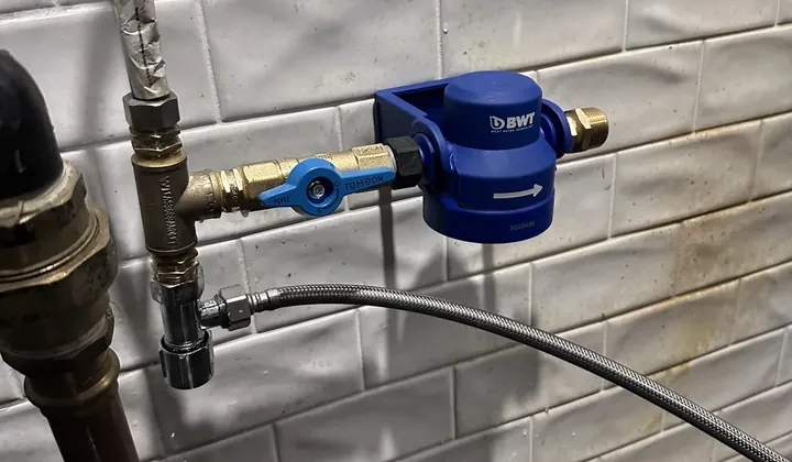 New filter head, brass isolation valve and tee fitting with a braided hose on the water line in a Sydney CBD commercial kitchen