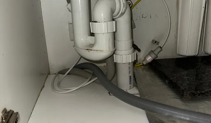 Water filter housings and tubing beside the waste pipes under a kitchen sink in Kings Langley