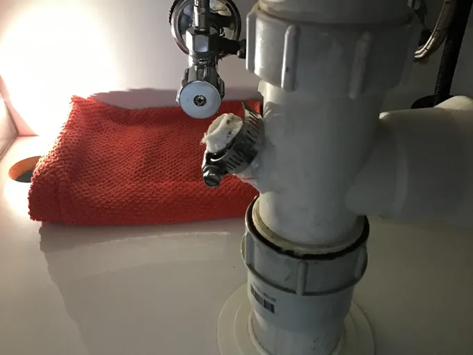 Chrome isolation valve and a dishwasher waste connection under a kitchen sink in Oxley Park