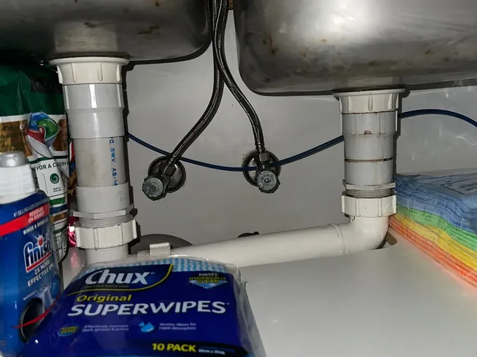 Braided hoses and isolation valves under a double kitchen sink in Kings Langley