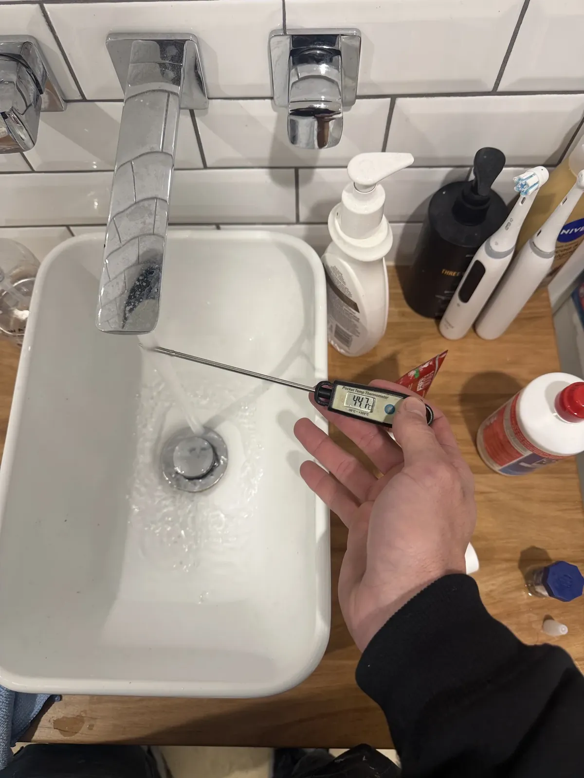 Zip Hot Water Sydney - Thermometer held under a running bathroom basin tap to check the hot water temperature in Tamarama