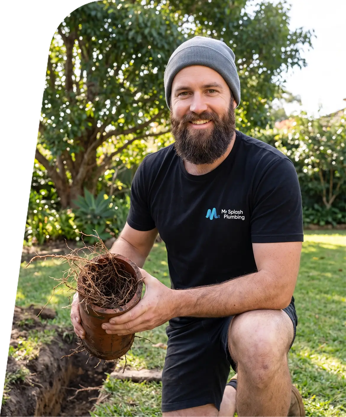 Plumber in a backyard holding a section of drain pipe packed with tree roots